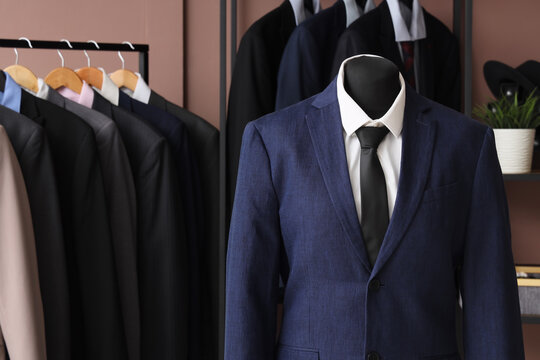 Shelving unit, rack and mannequin with different stylish male suits in dressing room
