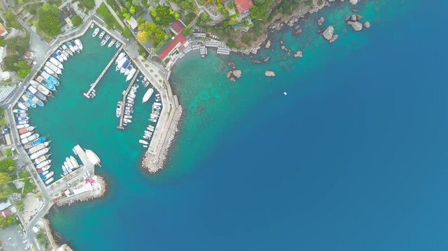 Antalya, Turkey. Top-down aerial view of Kaleici Old Town marina, terracotta rooftops, and the historic Hidirlik Tower on the rocky Mediterranean shore. Aerial View