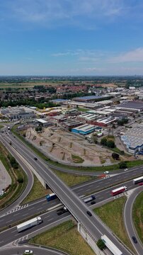 Aerial View of an Industrial Hub: An expansive aerial shot showcases a bustling industrial zone interlinked by a complex highway interchange, illustrating urban development and logistical networks.