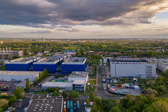 Aerial view of the Digital Realty Frankfurt FRA30 data center complex with large blue buildings and surrounding greenery under a cloudy sunset sky in Frankfurt am Main, Hessen, Germany.