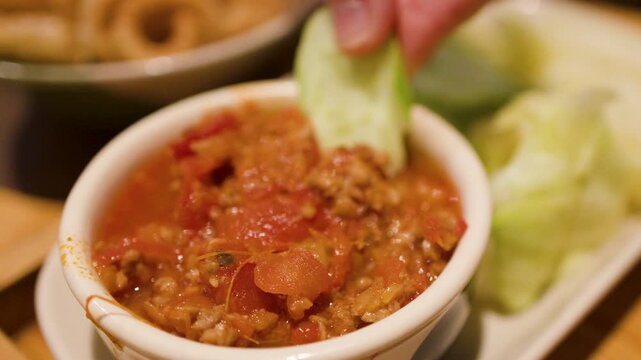 Dipping Pork Crackling and Cucumber into Northern Thai Nam Prik Ong