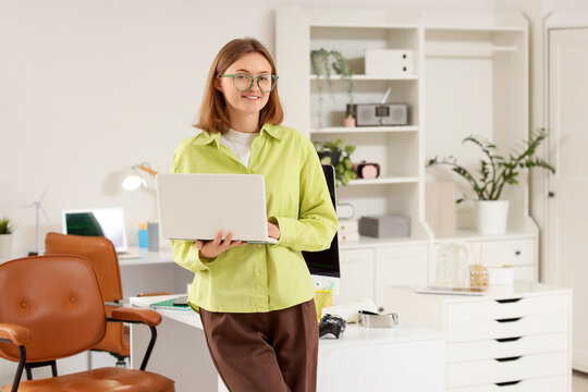 Happy female programmer with laptop working in office