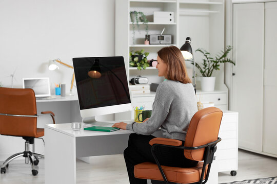 Happy female programmer with computer working in office
