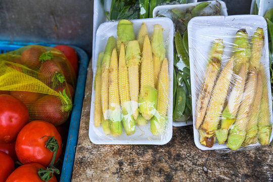 Fresh raw bap bao tu baby corn cobs in plastic wrap displayed at a traditional street vegetable market stall in Hoi An ancient town Vietnam