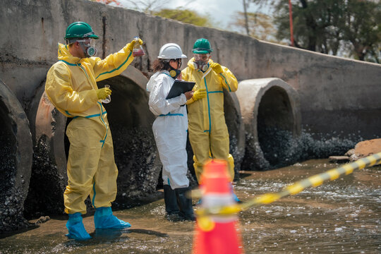 Scientists collecting polluted liquid samples from contaminated drainage canal to evaluate industrial wastewater toxicity and environmental damage in coastal ecosystem area.