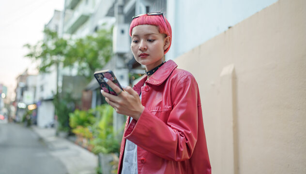 Traveler Gen z girl leather fashion with punk Asian woman tourist&nbsp;in city street searching location in map application online smart phone using GPS&nbsp;navigating