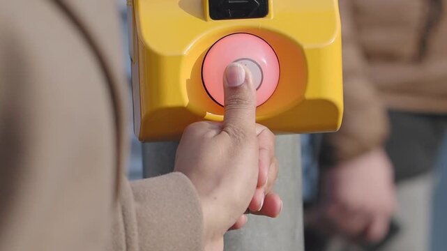 Pedestrian presses button at crosswalk for signal
