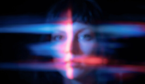 An abstract portrait of a person with soft features, overlaid with colorful light streaks creating a dreamy and surreal effect against a dark background.