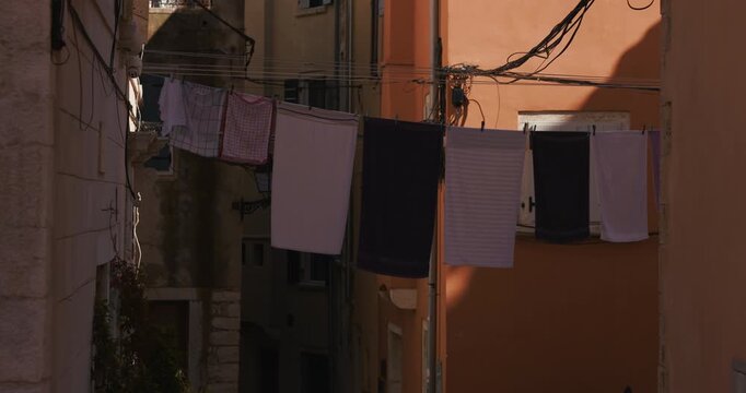 Laundry hanging on clotheslines between buildings in a narrow old town street.