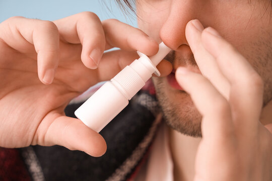 Ill young man with nasal drops at home