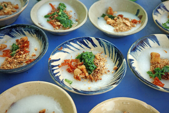 close-up view of traditional vietnamese banh beo rice cakes in small vintage pattern clay bowls topped with vibrant green scallion oil dried shrimp flakes and roasted peanuts