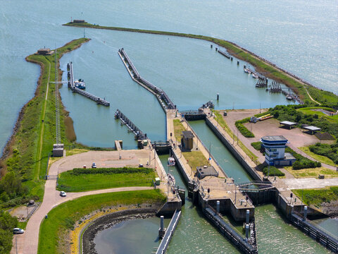 Aerial view of the Lorentzsluizen lock complex with water gates and piers surrounded by green embankments, Kornwerderzand, Friesland, Netherlands.