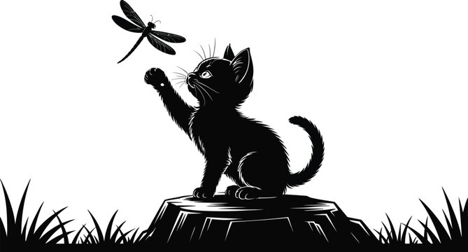 Black cat kitten playing with dragonfly on tree stump outdoors in grass