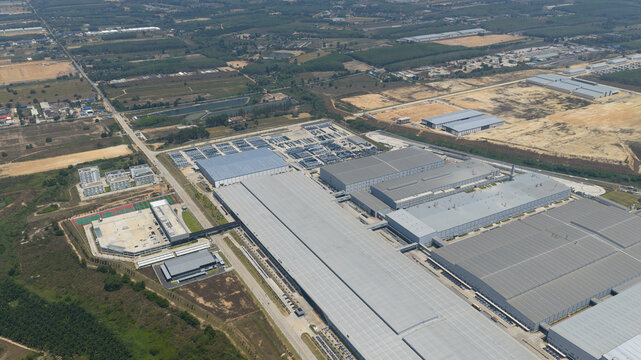 Aerial view of the BYD Thailand Rayong Office Building and industrial complex with modern factory structures and surrounding green fields in Phananikhom, Rayong, Thailand.