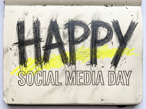 Happy social media day handwritten text in a sketchbook with yellow highlight