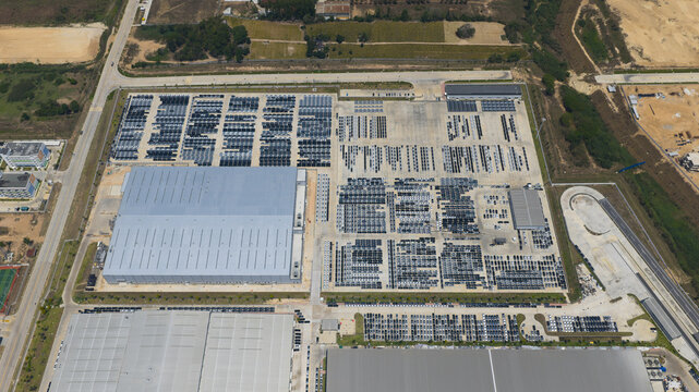 Aerial view of the BYD Thailand Rayong Office Building and large industrial factory complex with rows of parked vehicles and surrounding fields Phananikhom, Rayong, Thailand.