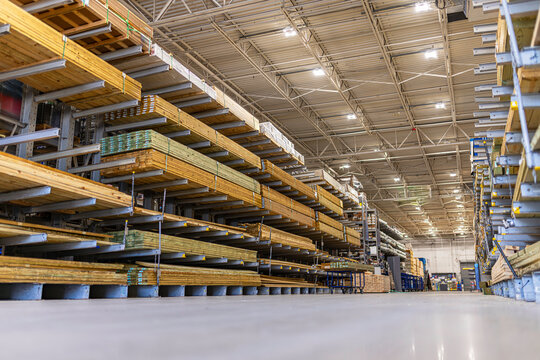 Low-angle view of organized stacks of lumber and pressure-treated wood boards stored on heavy-duty cantilever racks inside a large home improvement warehouse store, USA