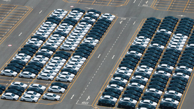 Aerial view of rows of new cars parked in a large logistics lot at the BYD Thailand Rayong Office Building in Phananikhom, Rayong, Thailand.