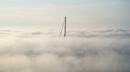 Fototapeta premium Towering Structure Piercing Through a Sea of Thick, White Clouds.