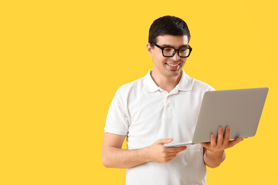 Male programmer with laptop on yellow background