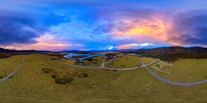 Aerial view of Rio Serrano Hotel and Spa near a winding river under a dramatic sunset sky with colorful clouds Torres de Paine, Magallanes y la Antar, Chile.