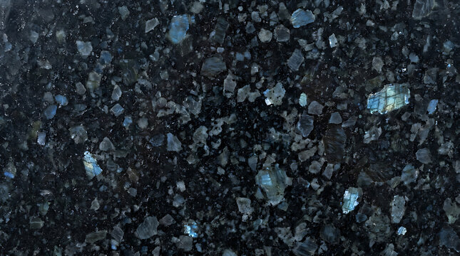 Polished black granite texture with shimmering blue labradorite crystals and natural mineral patterns for luxury interior design.