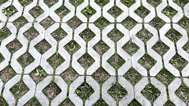 Decorative sidewalk made of figured grey concrete tiles in the shape of diamonds.