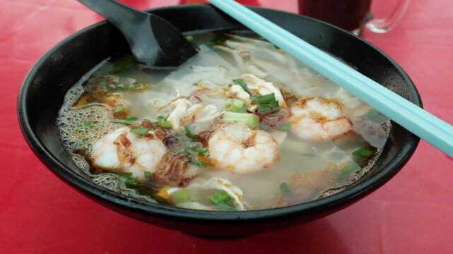 Steaming hot bowl of authentic Malaysian Kai Si Hor Fun shredded chicken noodle soup with prawns at a kopitiam.