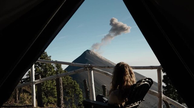 Traveler watching Fuego volcano eruption from campsite viewpoint on Acatenango volcano in Guatemala