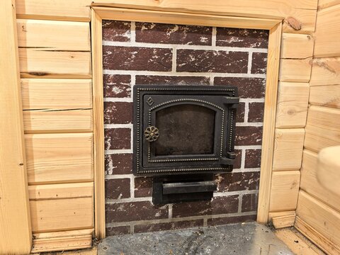 Sauna stove firebox in wooden bathhouse interior