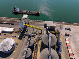 Ship docked at a port with grain silos and loading equipment © Denys