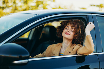Fototapeta premium A cheerful woman drives a car with a relaxed smile, natural light in the cabin, and a retro film vibe. Concept for lifestyle joy and travel in a candid automotive moment.