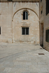 Fototapeta premium Architecture of a historic limestone building with traditional windows and stone paved square in Dubrovnik Old Town Croatia