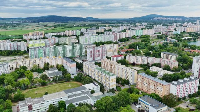 Cinematic aerial drone footage of Petržalka housing estate in Bratislava, Slovakia. Dense residential district with colorful apartment buildings, urban landscape and surrounding countryside.