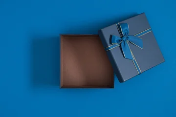 Flat Lay of Open Empty Dark Blue Gift Box with Bow on Blue Background. Top View Minimalist Christmas, Birthday or Father's Day Present Composition with Copy Space for Text.  © prime1001