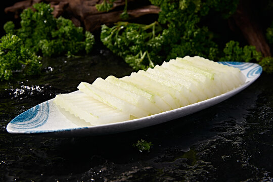 Hot pot with melons and vegetables, including slices of wavy winter melon with skin.
