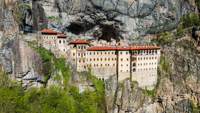 aerial drone view of the ancient Sumela Monastery built into a steep cliff face in the forest mountains of Trabzon, Turkey 