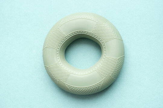 Close-up of a round rubber hand expander on a mint background