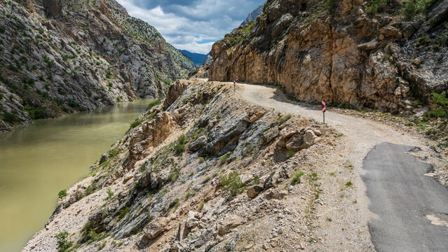 Aerial perspective flying through the deep Dark Canyon in Kemaliye, Turkey. Drone shot following the path of the Karasu River with the legendary hand-carved Stone Road visible on the cliff