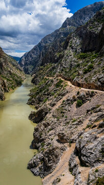 Aerial perspective flying through the deep Dark Canyon in Kemaliye, Turkey. Drone shot following the path of the Karasu River with the legendary hand-carved Stone Road visible on the cliff