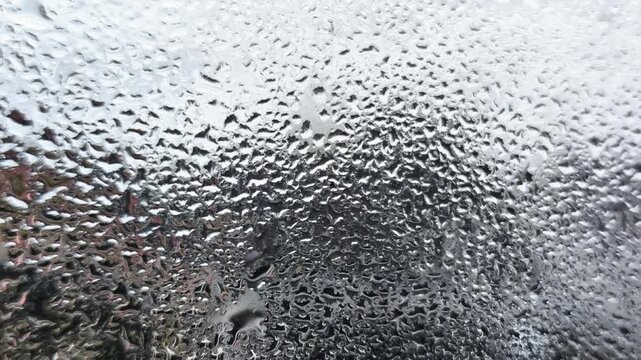 Beautiful abstract background of heavy water condensation on window pane, macro shot of raindrops and moisture droplets on glass surface after rain, cold weather misty window texture wallpaper