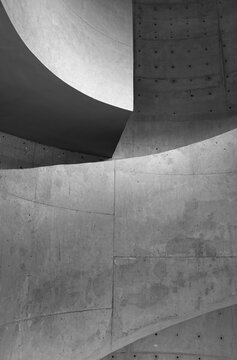 Monochrome architectural study of curved concrete walls and ramps creating bold geometric shapes, textures and negative space, a minimalist, brutalist composition emphasizing form, repetition and