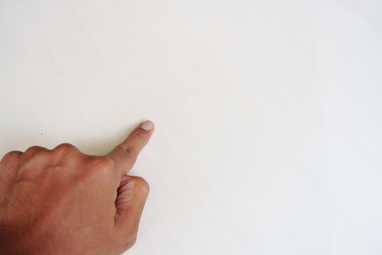 An adult hand pointing his index finger at a clean white background with copy space.