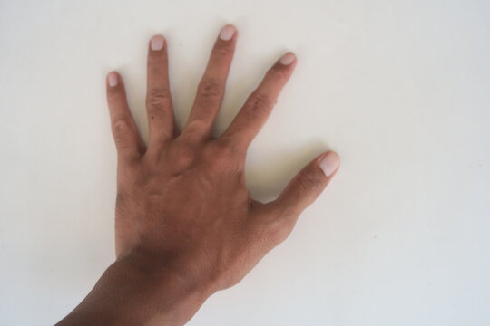 Top down view of a male hand with fingers spread open on a plain white background.