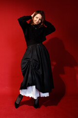 Naklejka premium Confident woman in black dress, standing with one hand behind head
