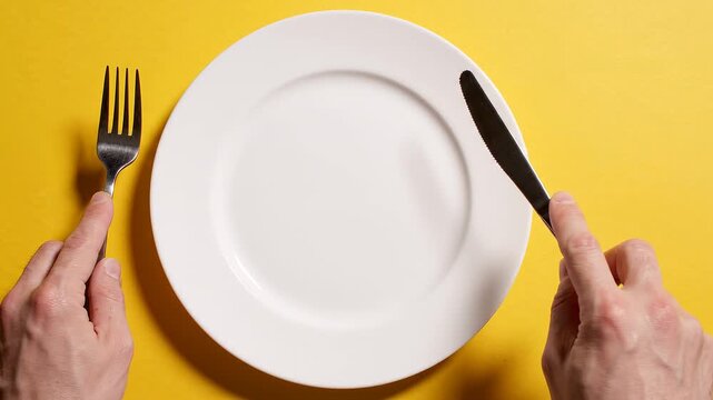 Hands holding fork and knife plate.