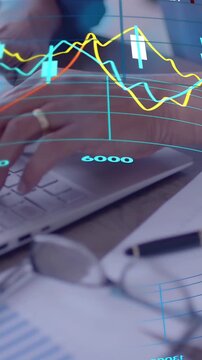 Vertical video: Mature man typing on laptop, activating animated finance charts for tracking values
