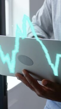 Vertical video: Man bringing laptop, tilting, typing while analyzing finance as holo chart on hands