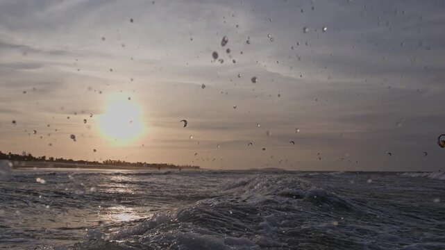 Ocean waves roll beneath a kitesurfing POV near Pre&aacute;, Cear&aacute;, Brazil, with sunset light reflecting across tropical Atlantic water, action water sports shot at sea level.