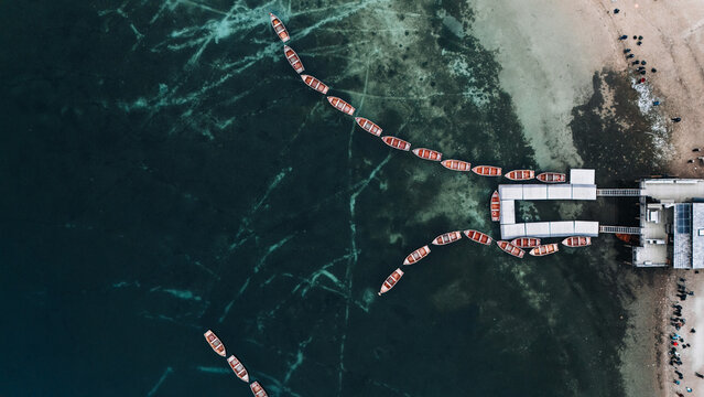 Aerial view of wooden rowing boats lined up on the emerald green water of Lake Braies near the wooden pier Braies, Trentino-Alto Adige, Italy.